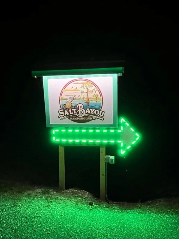 The sign for Salt Bayou Kampground RV Park at night
