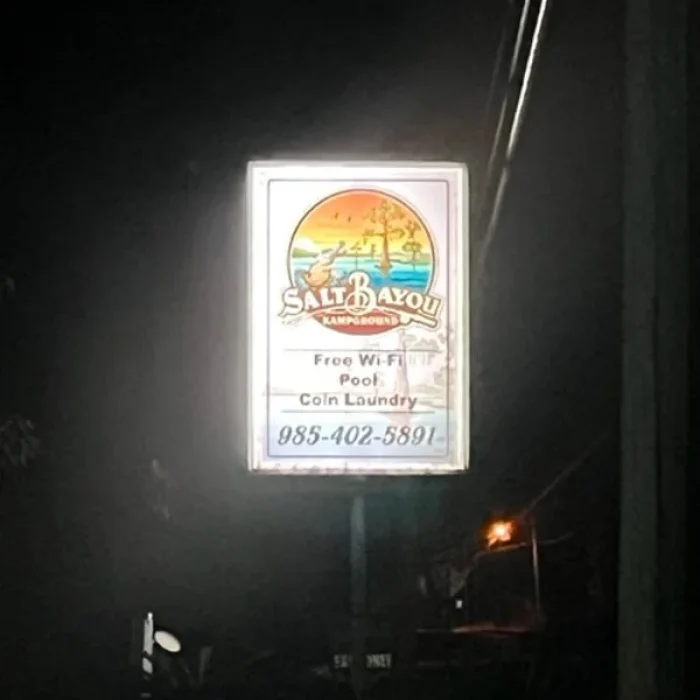 The sign for Salt Bayou Kampground RV Park lit up at night